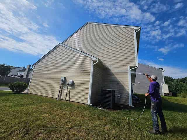 Home exterior maintenance with pressure washing on a beige house